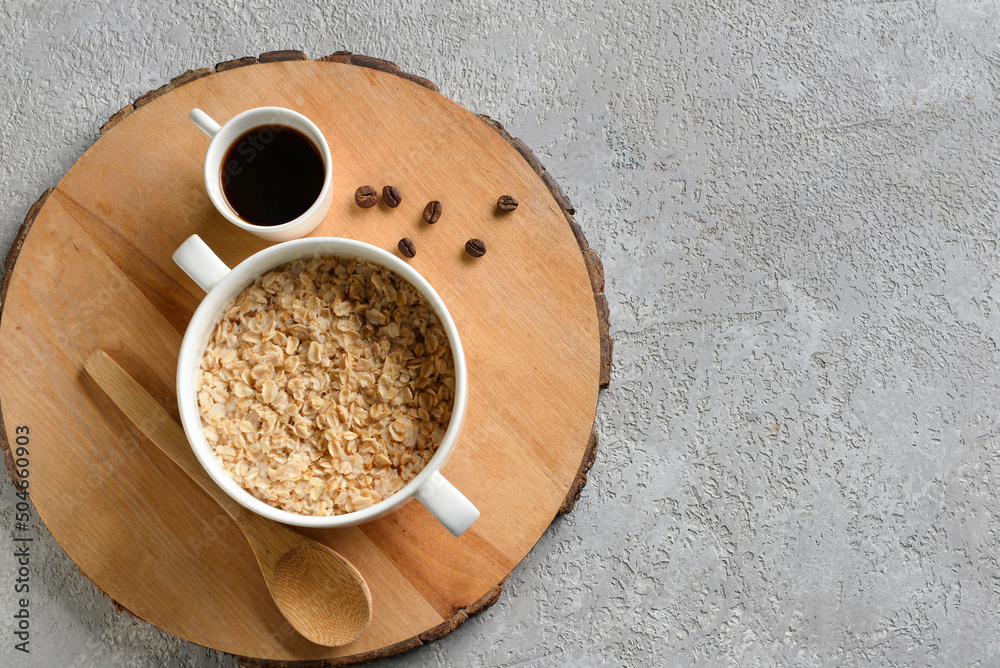 Pot of tasty oatmeal and cup with coffee on grey background