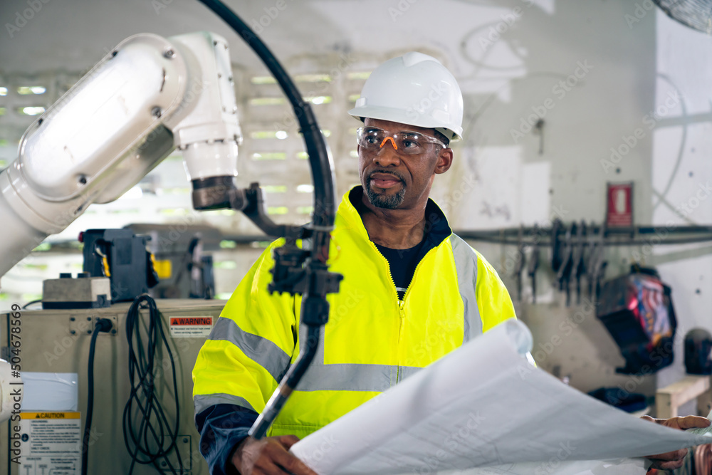 African American factory worker working with adept robotic arm in a workshop . Industry robot progra