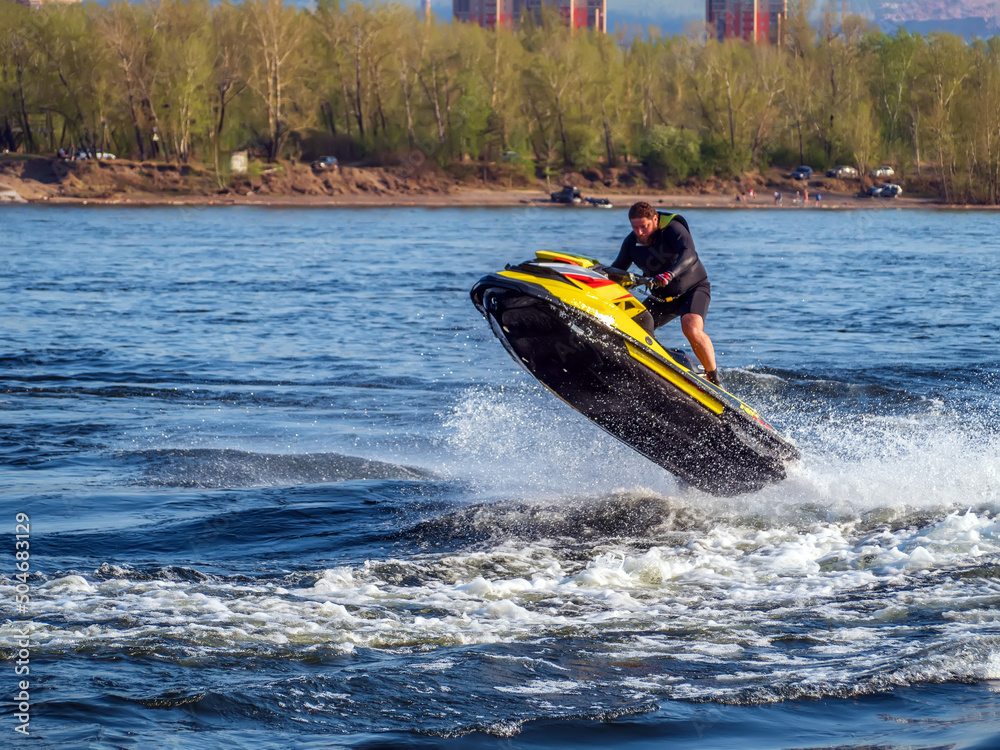 Guy is jumping on a water scooter at high speed.