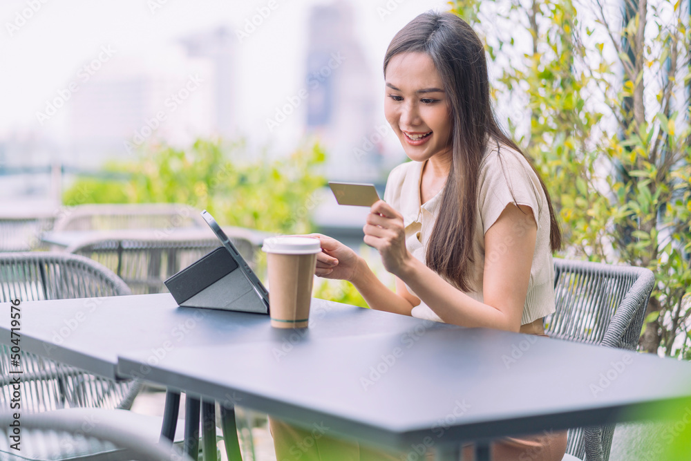 Asian woman is buying online and paying with credit card.female sitting at the cafe outdoor enjoying