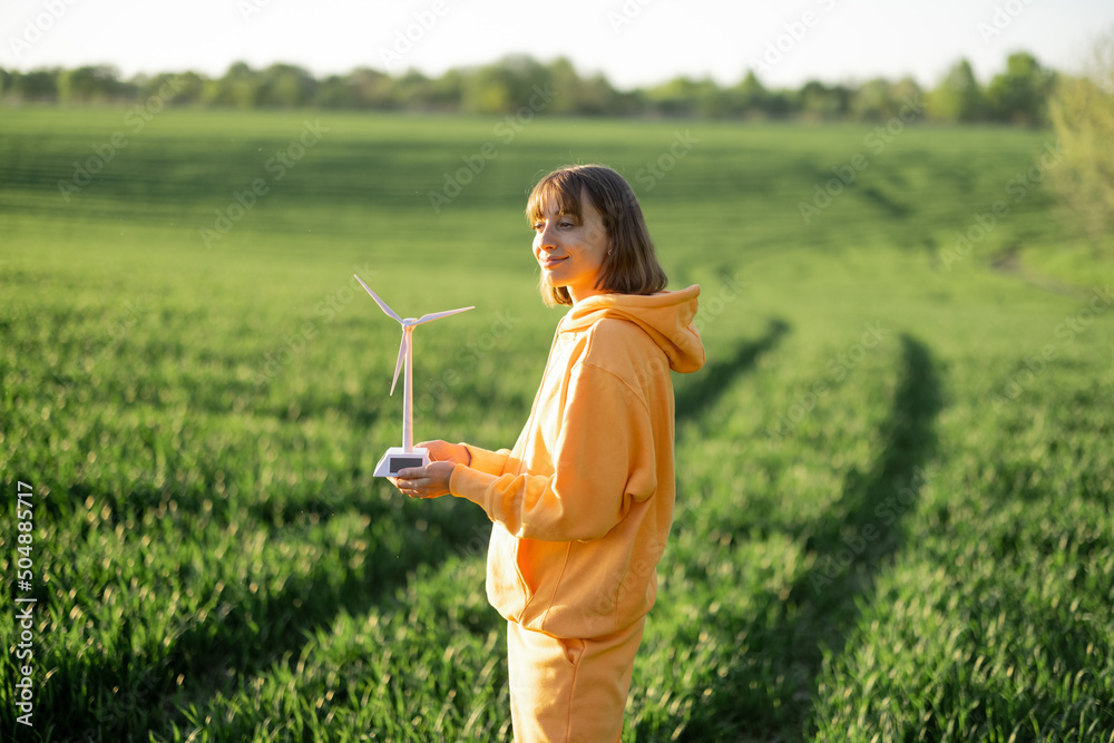 Woman with toy wind generator on green field