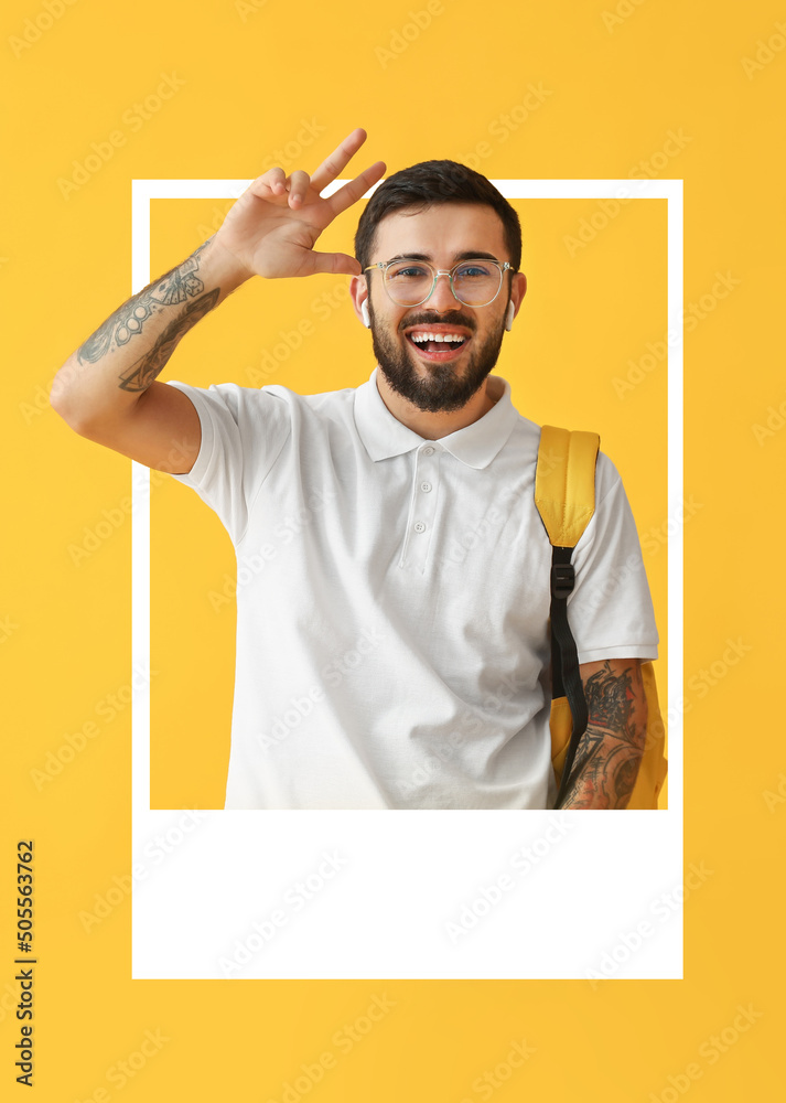 Handsome tattooed male student looking out of frame on yellow background