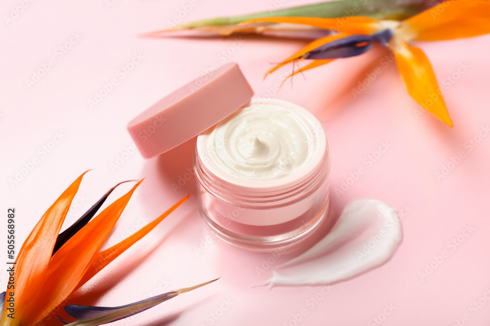 Jar of cream and strelitzia flowers on pink background