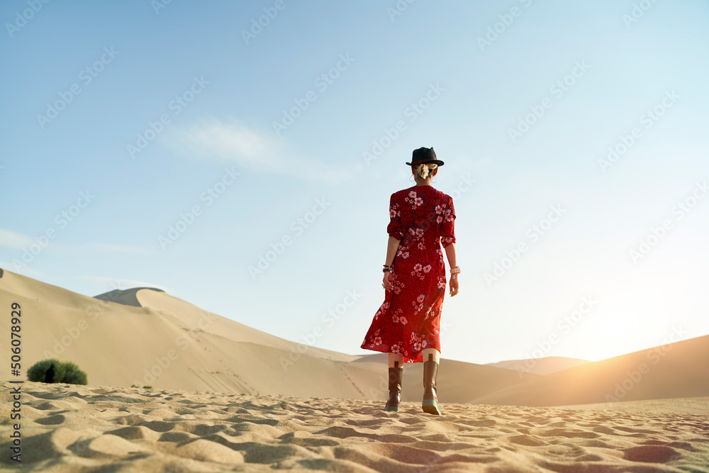 asian woman walking in desert under blue sky