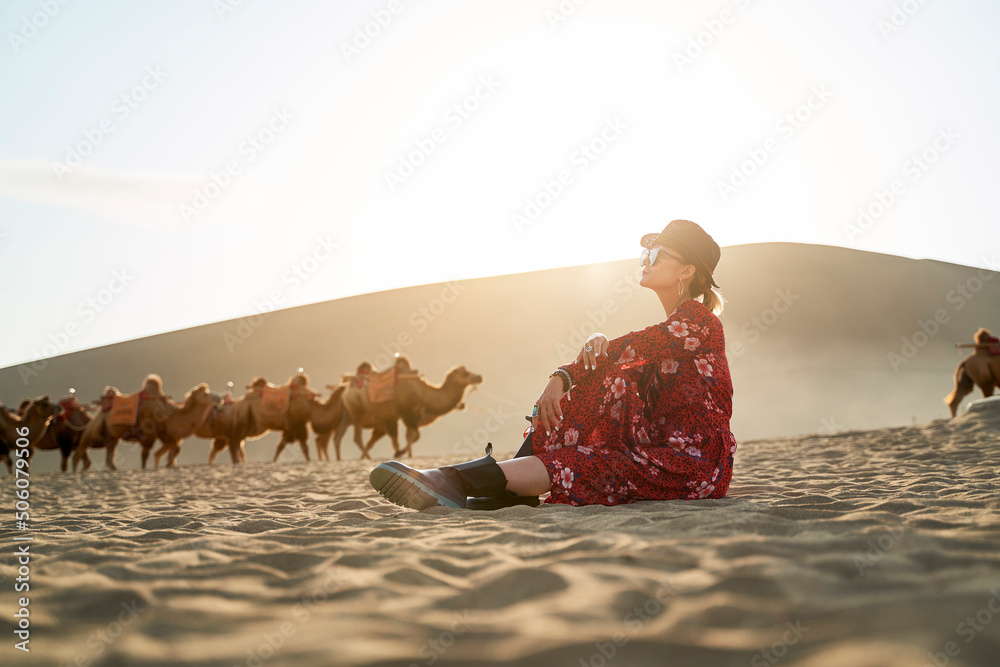 穿着红色连衣裙的亚洲女子在沙漠中眺望风景