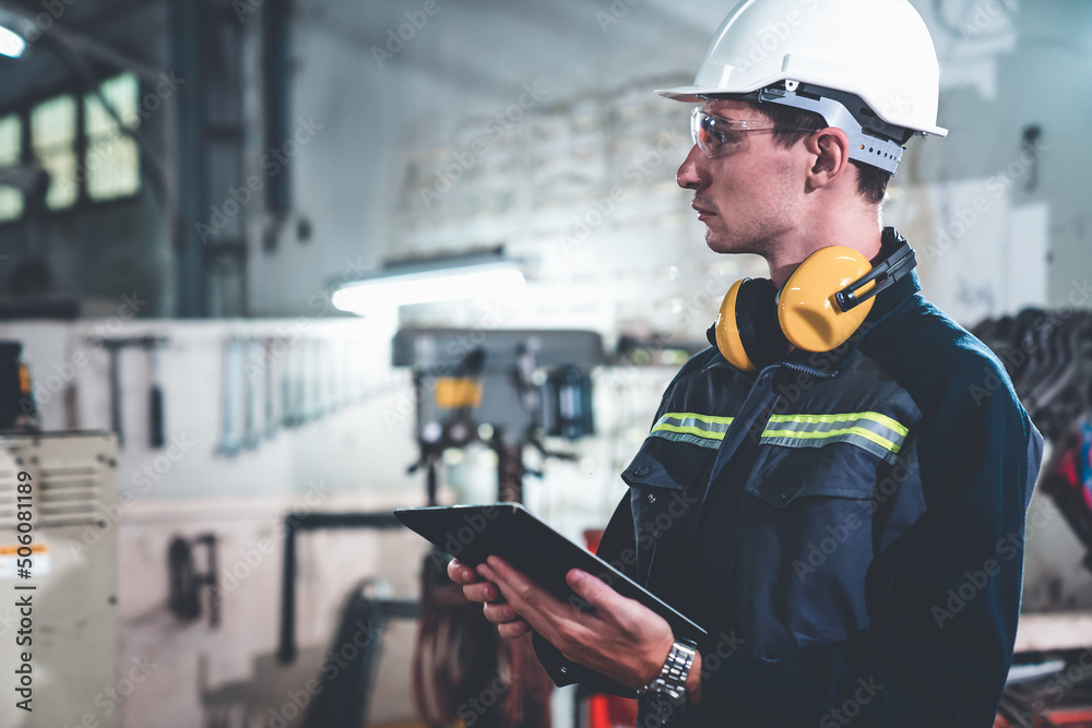 Young factory worker using adept tablet computer in a workshop building . Industrial technology and 