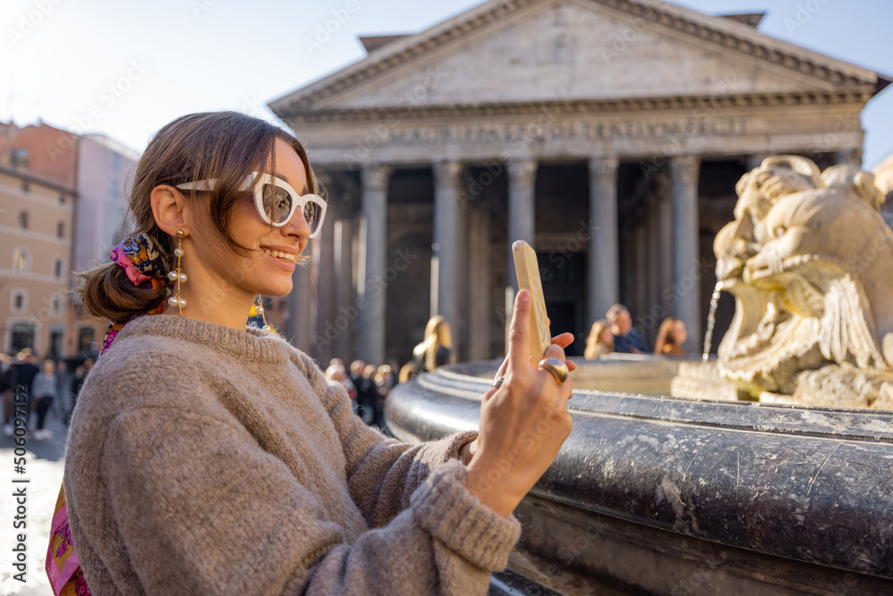 Young female traveler talking on phone while standing in front of famous Panthenon temple and founta