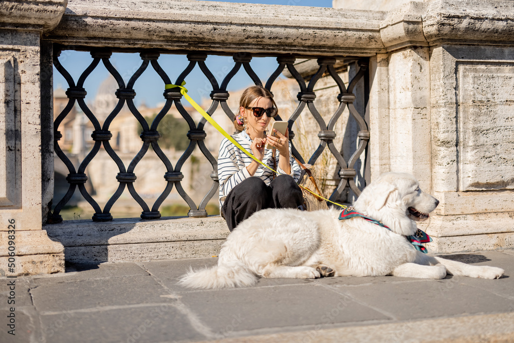 Woman with her white dog sitting on the street in Rome. Elegant woman with italian shepherd dog. Con