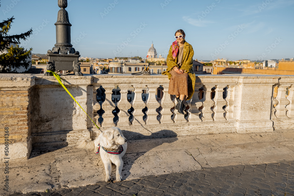 Woman enjoys beautiful cityscape of old Rome city, standing back with her dog on the top of Spanish 