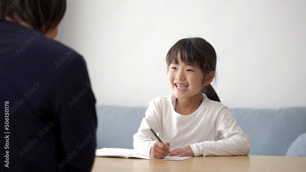 家で勉強をする女の子と見守るお母さん