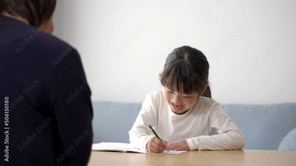 家で勉強をする女の子と見守るお母さん