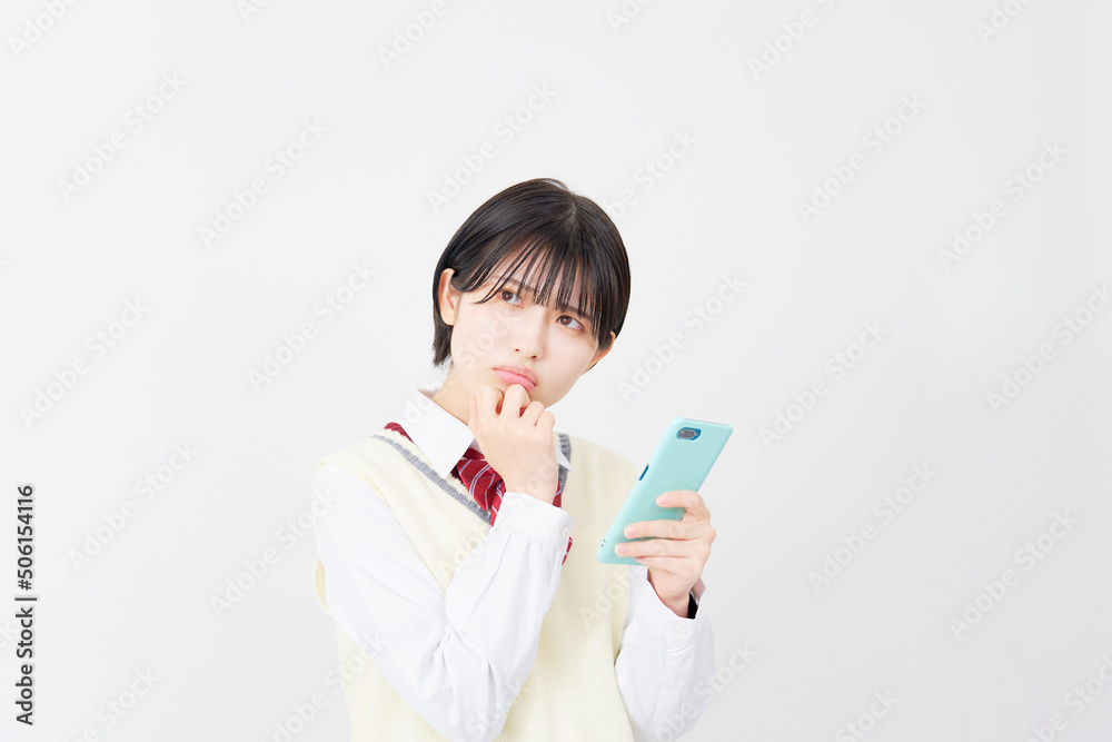 白背景でスマホを持って考える女子高生