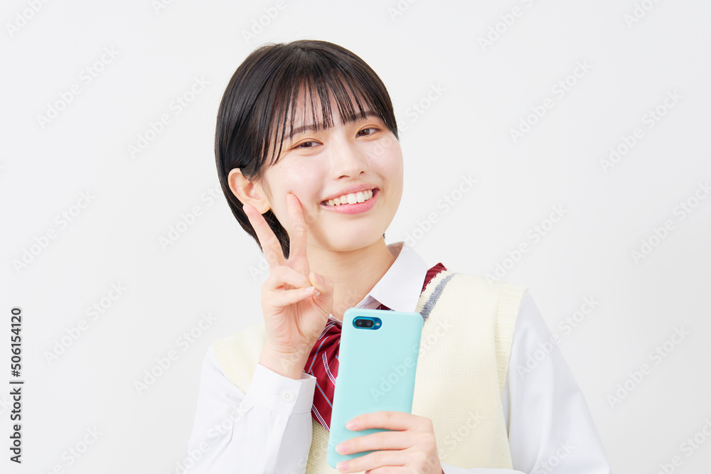 白背景でスマホを持ってピースサインをする女子高生