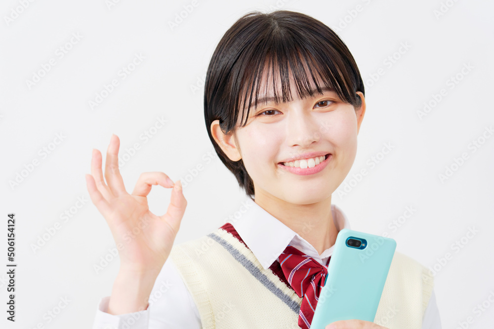 白背景でスマホを持ってOKサインをする女子高生