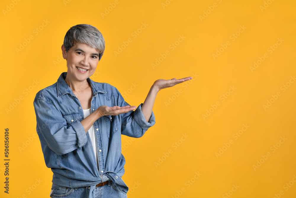 Middle aged Asian woman 50s showing empty copy space on the open hands palm for text or product isol