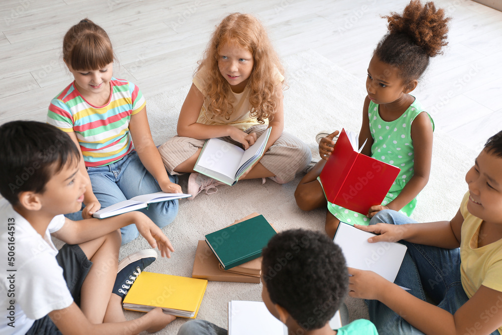 Little children reading books on floor