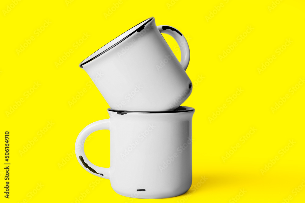 Two ceramic cups on yellow background