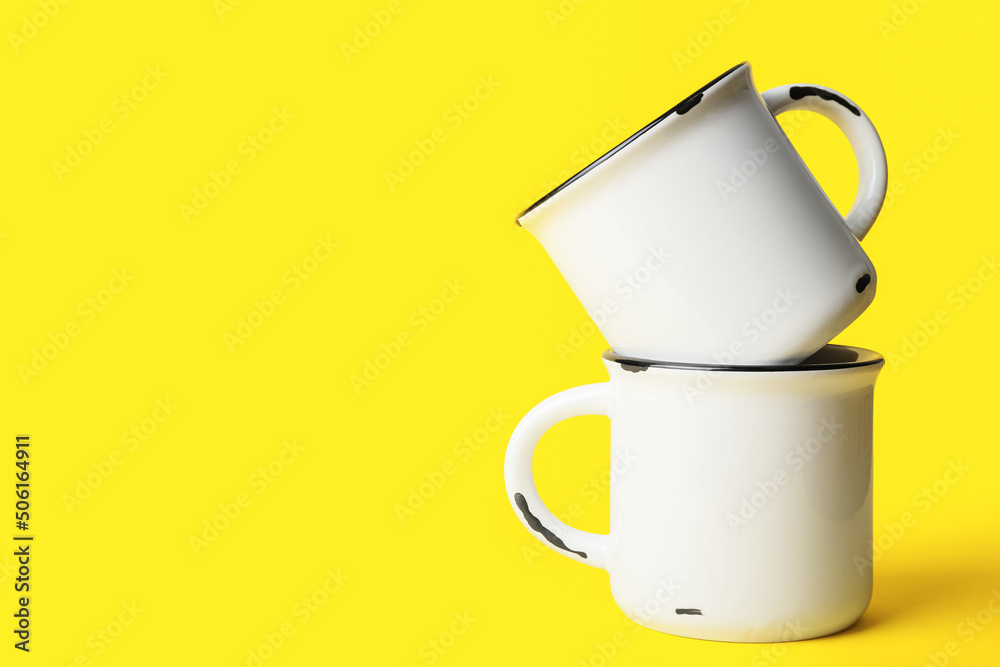 Ceramic cups on yellow background