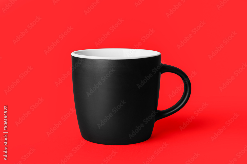 Black ceramic cup on red background