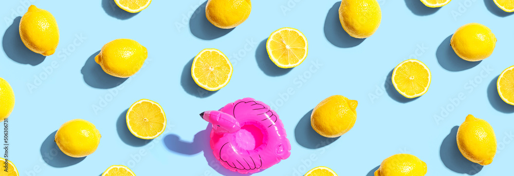 Summer concept with a pink flamingo float and lemons - flat lay