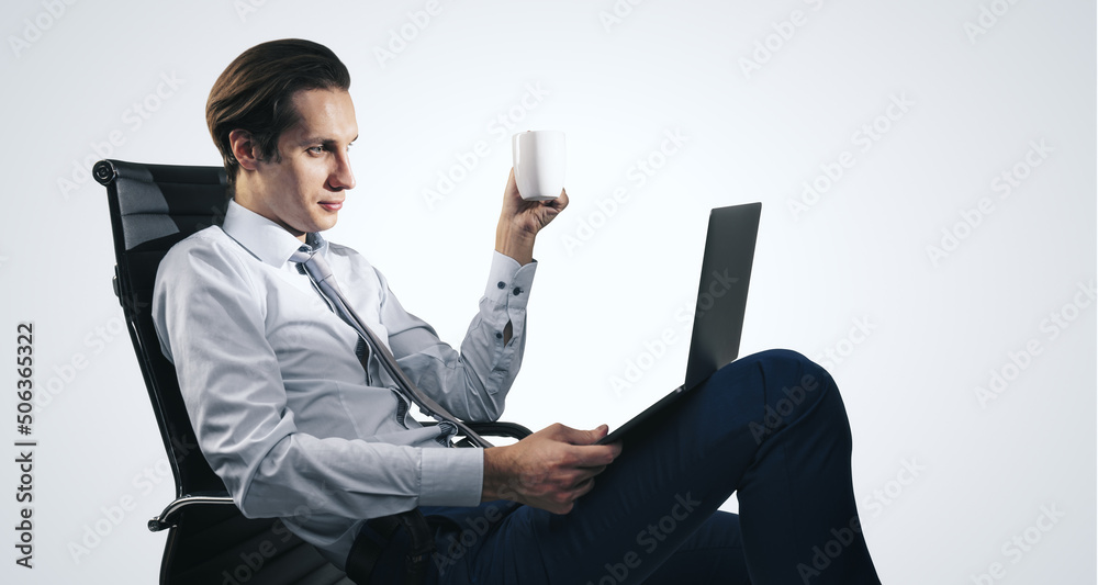 Distant work and freelance concept with man in white shirt sitting on office chair with cup of coffe