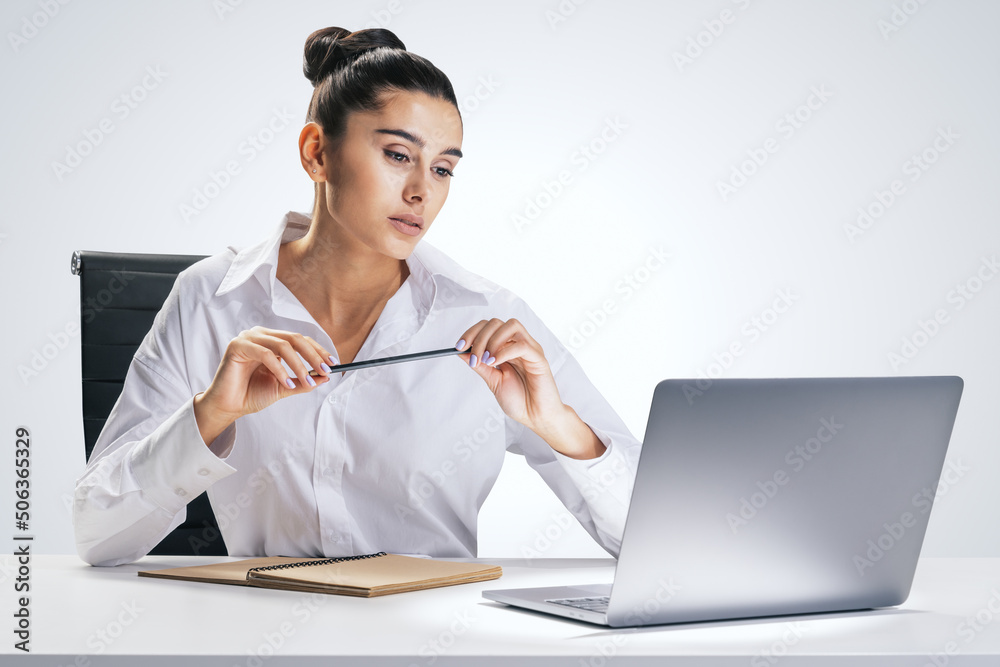 Business process and office work concept with pretty young woman sitting at white desk, looking at c