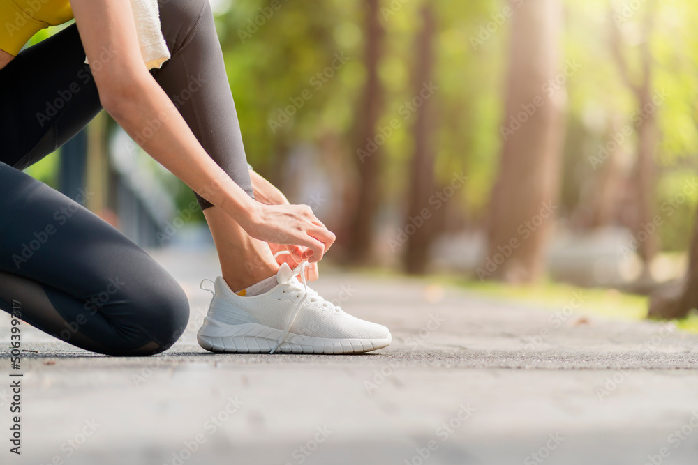 Asian Female sport woman athlete tying laces for jogging on road in the park running shoes at public