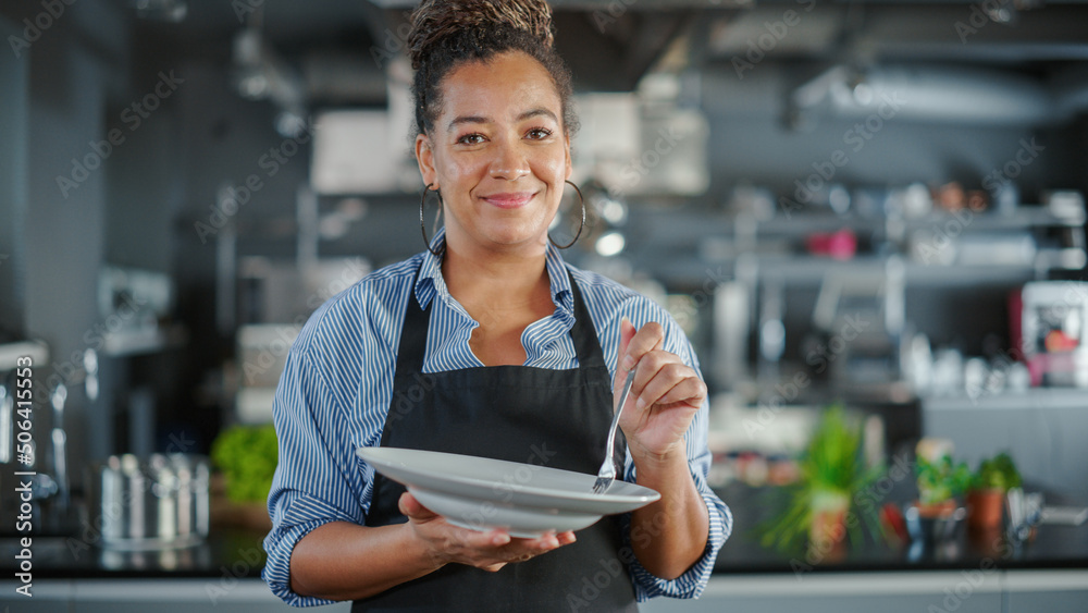 Restaurant Kitchen: Portrait of Black Female Chef Preparing Dish, Tasting Food and Enjoying it. Prof