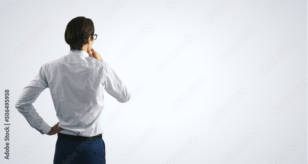 Thinking concept with pensive businessman in white shirt standing on abstract white wall backdrop, w