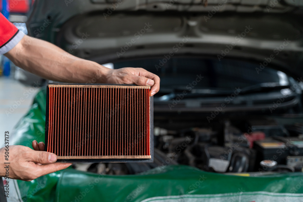 Auto mechanic is checking the engine filter in Car repair station.