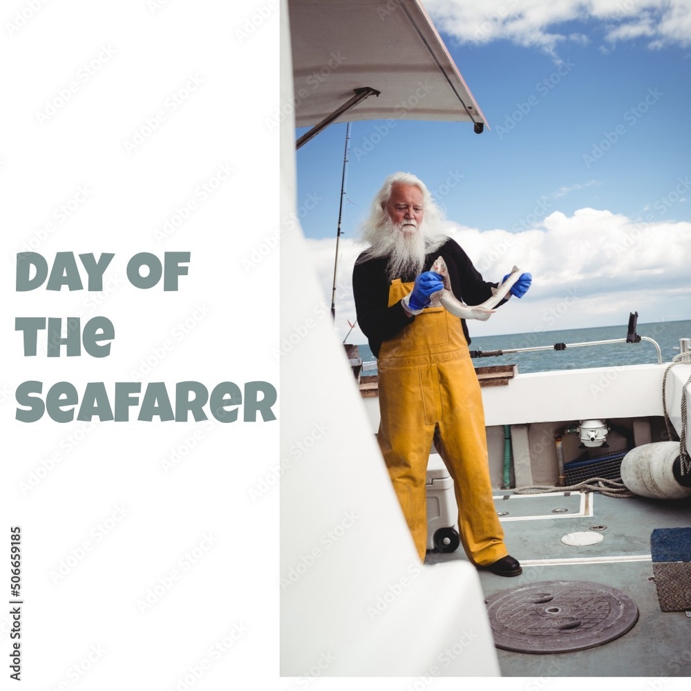 Senior caucasian man holding fish while standing in motorboat with day of the seafarer text