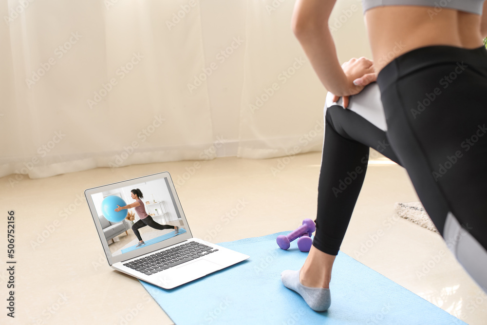 Sporty woman with laptop at home. Concept of online training