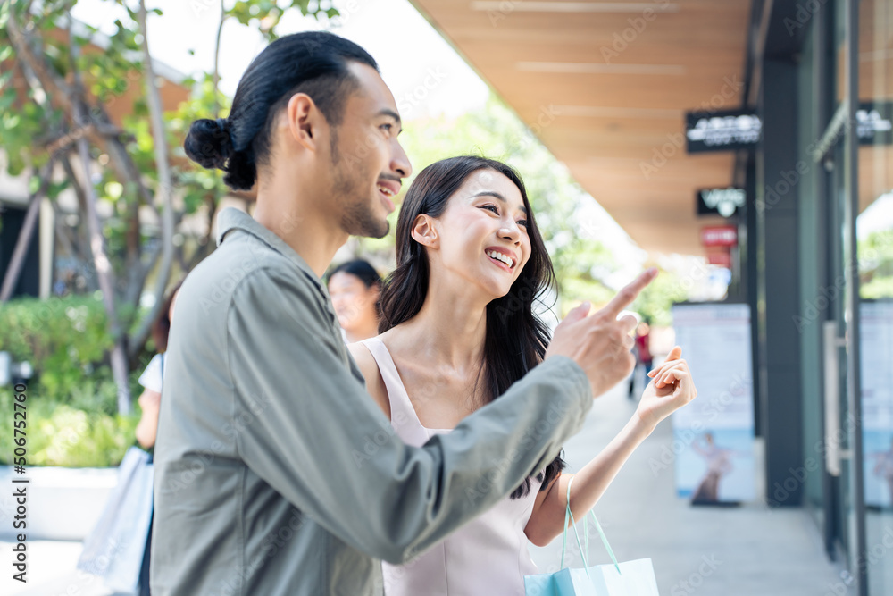 亚洲年轻男女在百货公司户外购物。