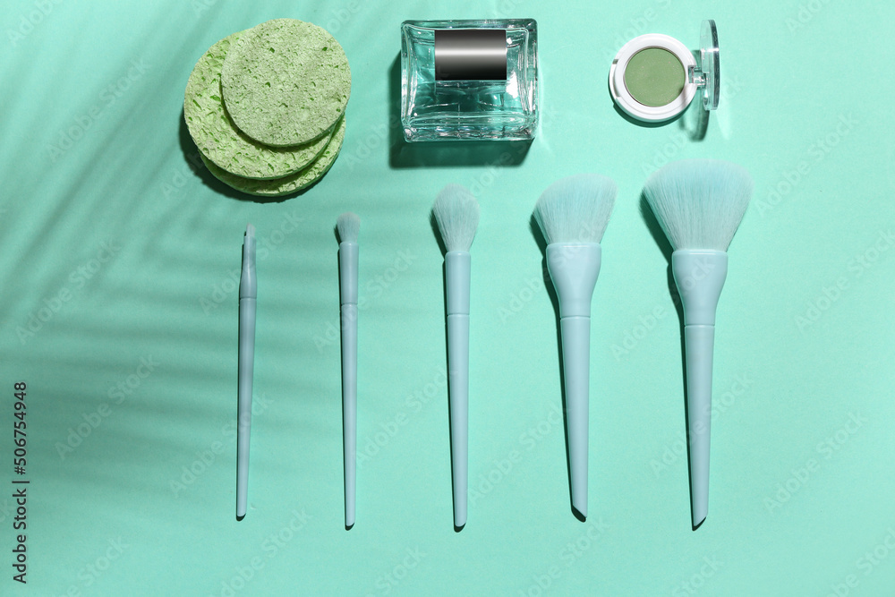 Makeup brushes with sponges, perfume and cosmetics on blue background