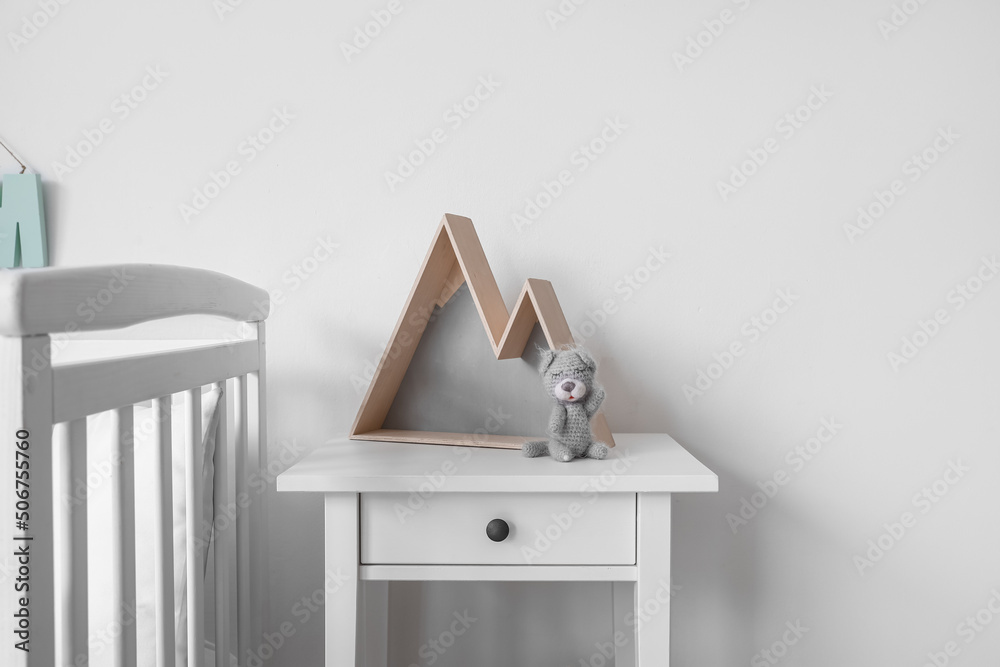 Table with toy and decor near light wall in nursery