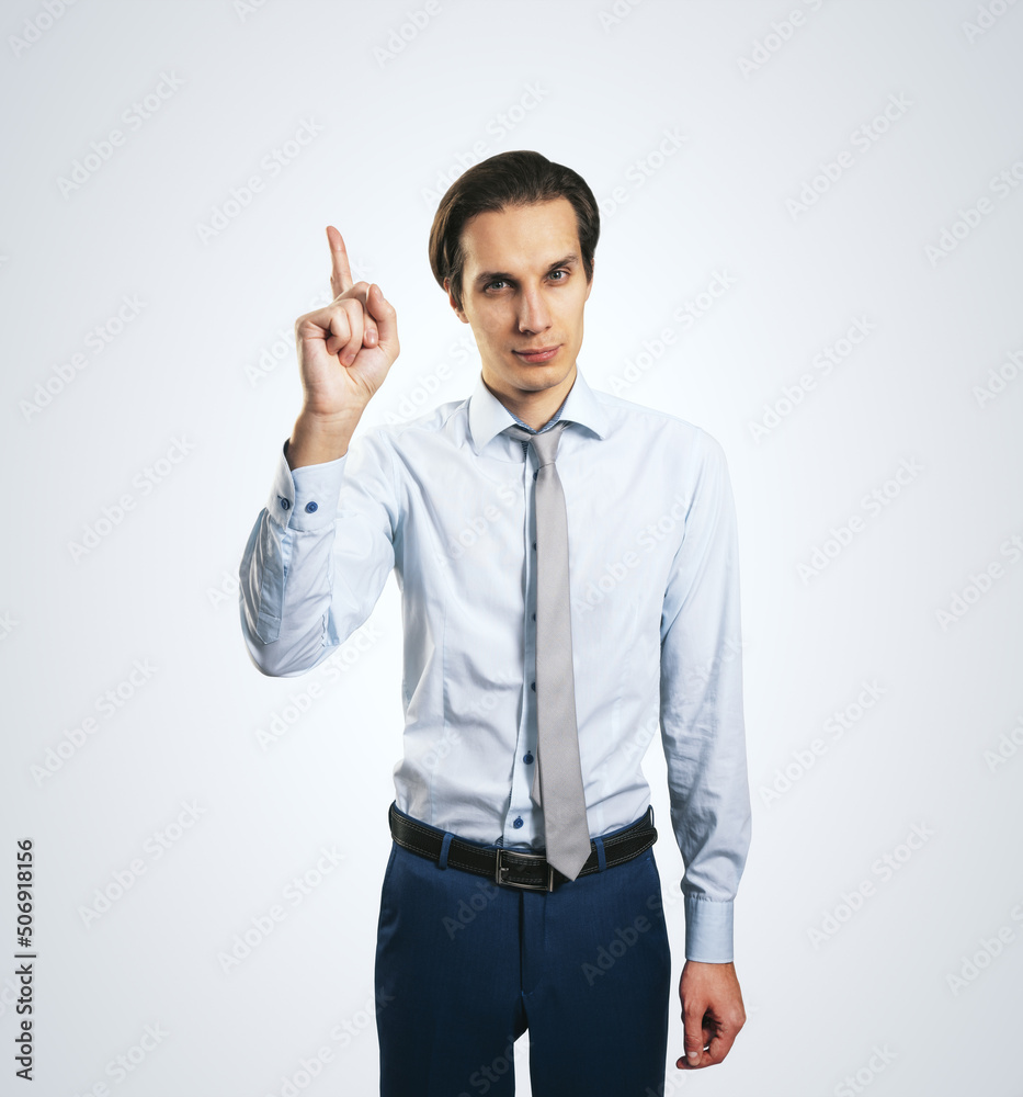 Warning concept wih young handsome man in white shirt with raising hand and forefinger isolated on l