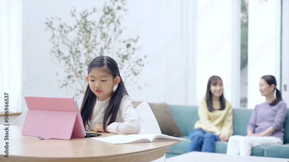 タブレットを使って学習をする女の子と見守る家族