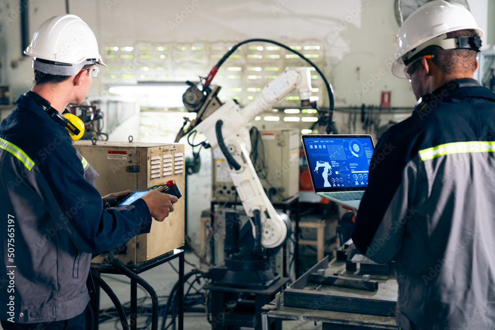 Factory workers working with adept robotic arm in a workshop . Industry robot programming software f