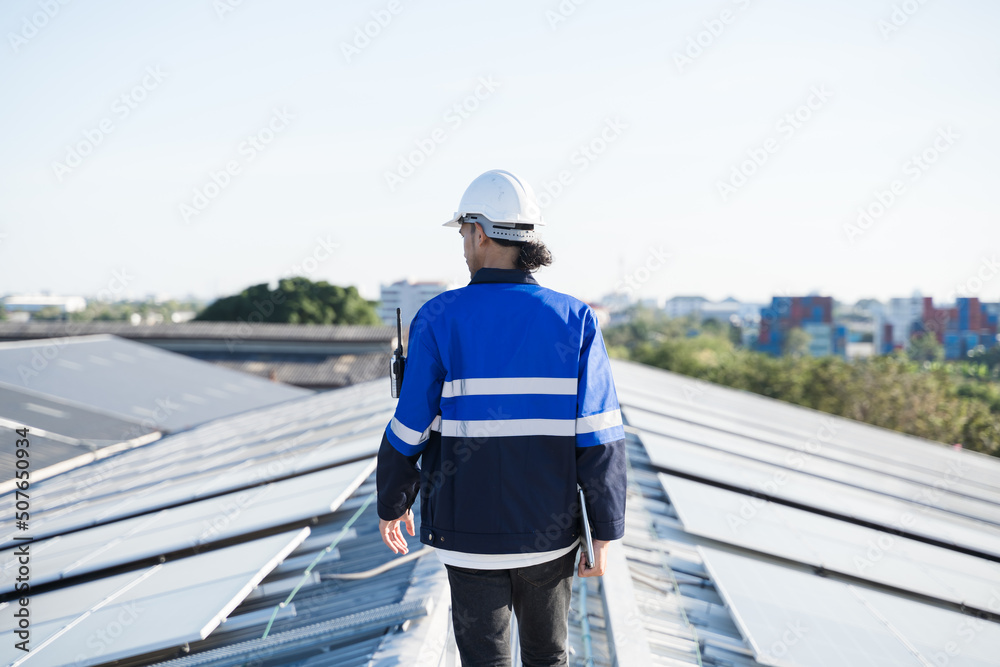 Portrait of Asian engineer on background field of photovoltaic solar panels solar cells on roof top 