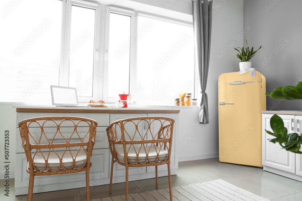 Interior of light modern kitchen with yellow fridge near big window