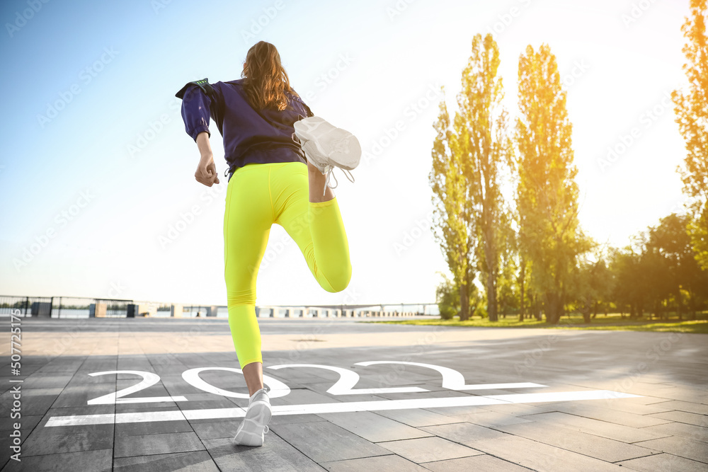 Sporty young woman running outdoors. Concept of 2022 goals