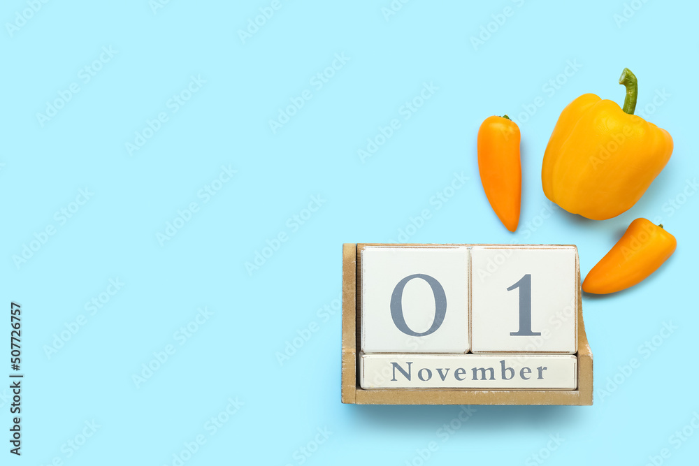 Cube calendar with date NOVEMBER 1 and fresh peppers on color background. World Vegan Day concept