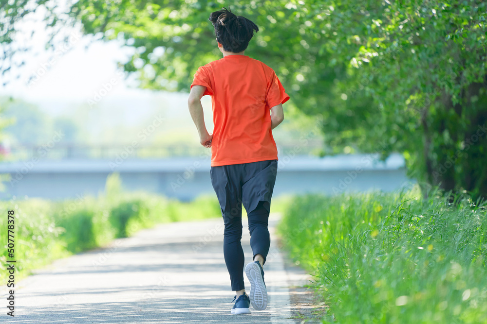 遊歩道をランニングする男性の後ろ姿