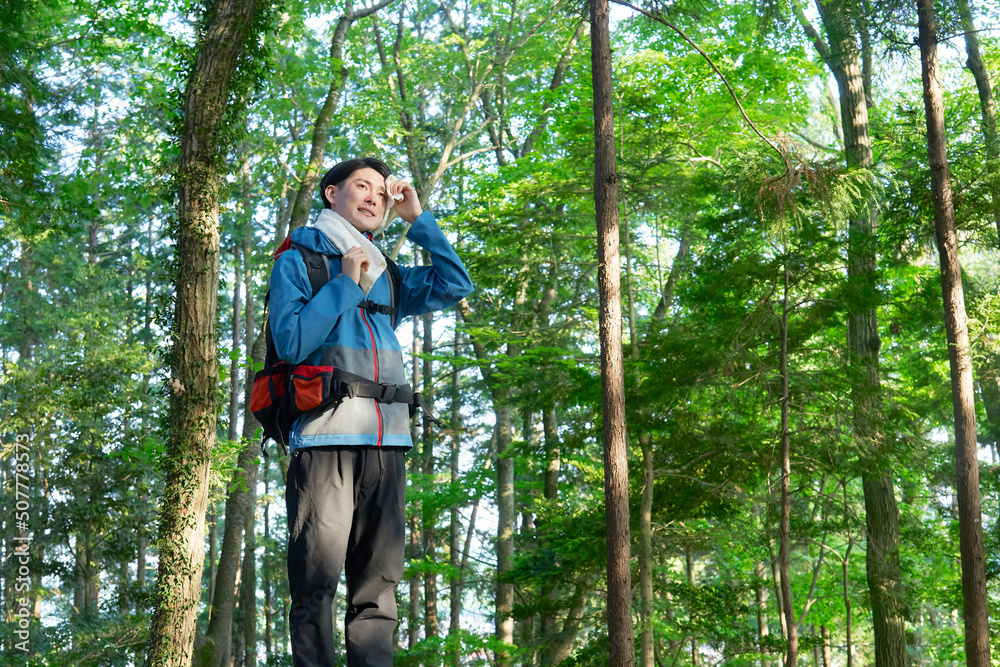 タオルで汗を拭く登山する男性