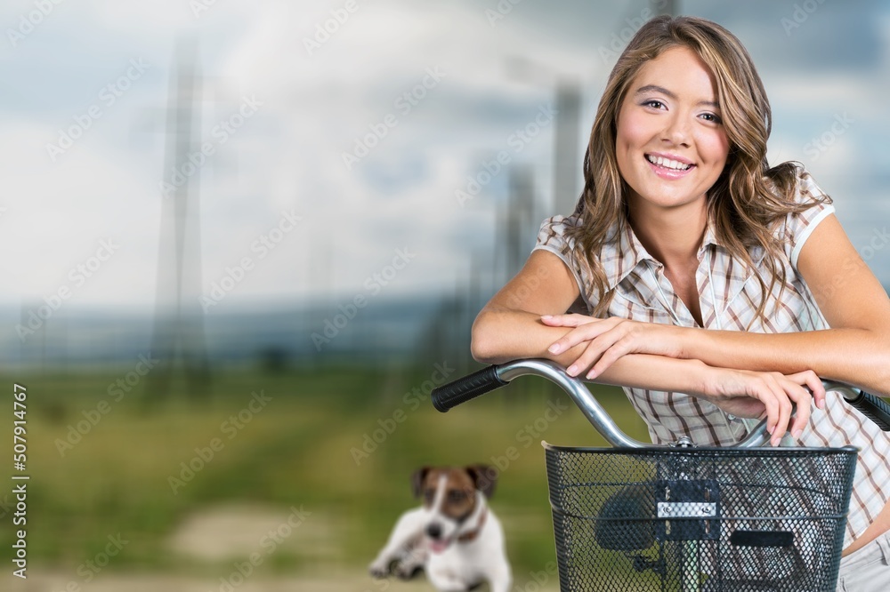 Woman cycling with a dog. Young woman riding bicycle together with her pet running nearby. Traveling