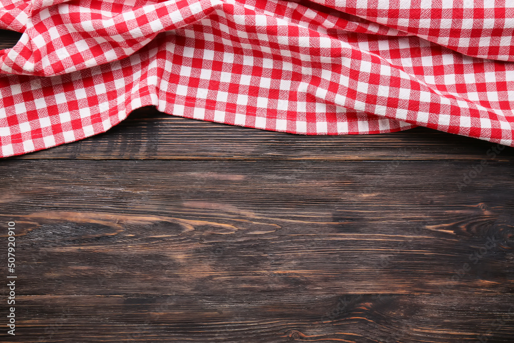 Red checkered tablecloth for picnic on dark wooden background