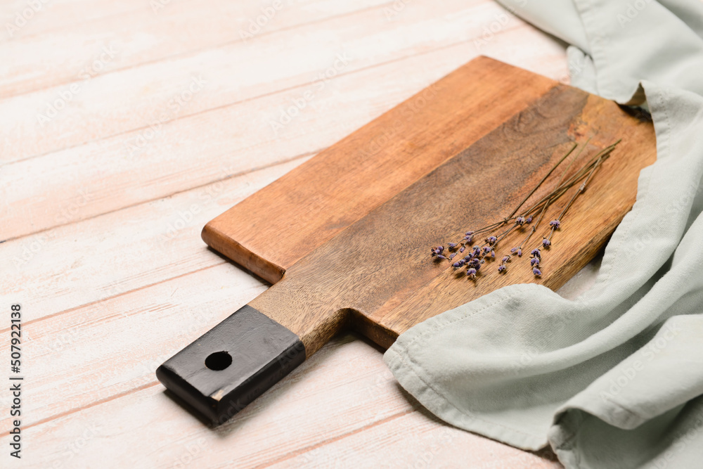 Cutting board and lavender flowers on light wooden background