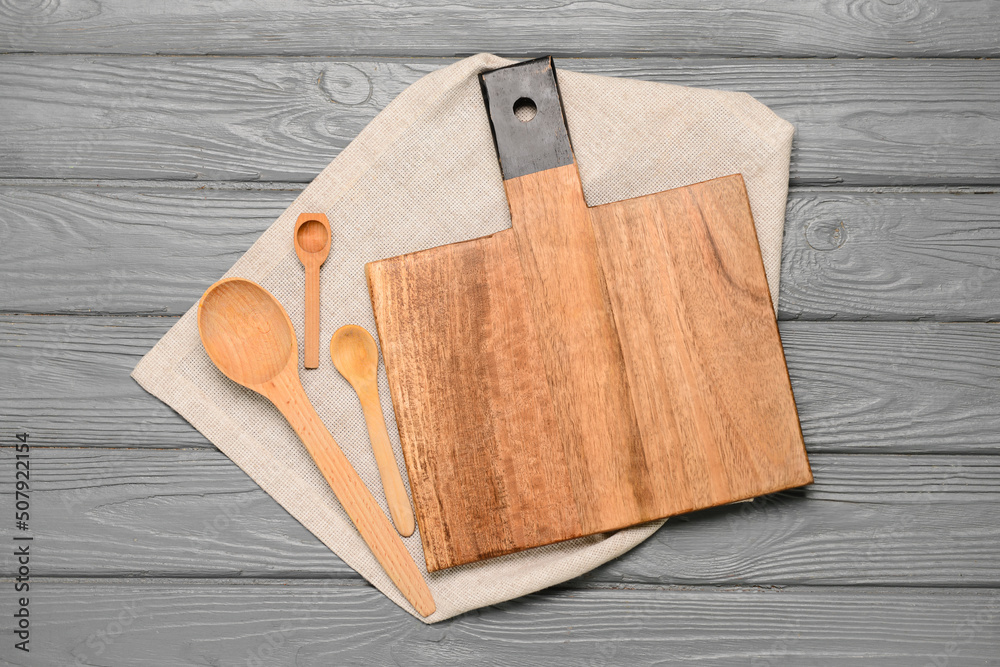 Cutting board and spoons on grey wooden background