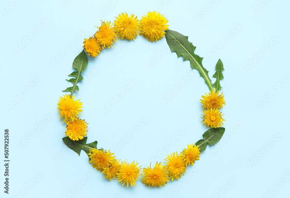 Frame made of yellow dandelions with leaves on blue background