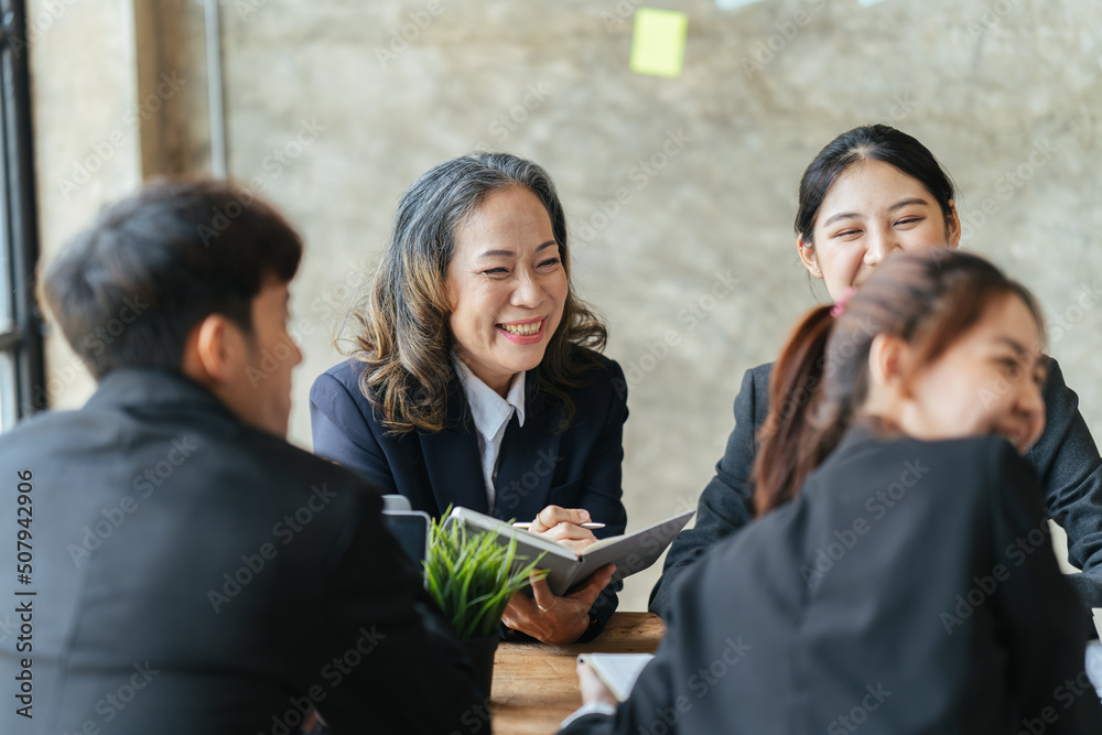 Group of young business people working and communicating while sitting at the office desk together, 